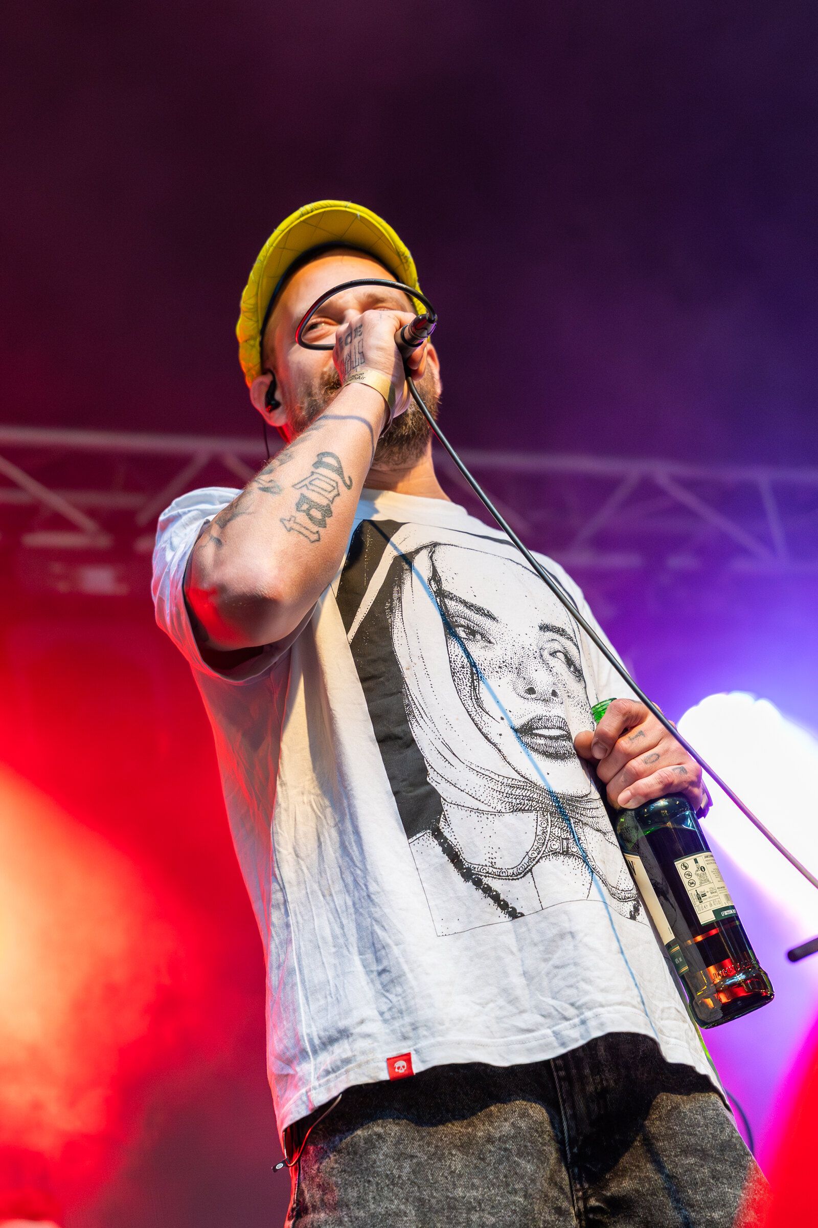 Rapper ve žluté kšiltovce zpívá v červeném a fialovém světle