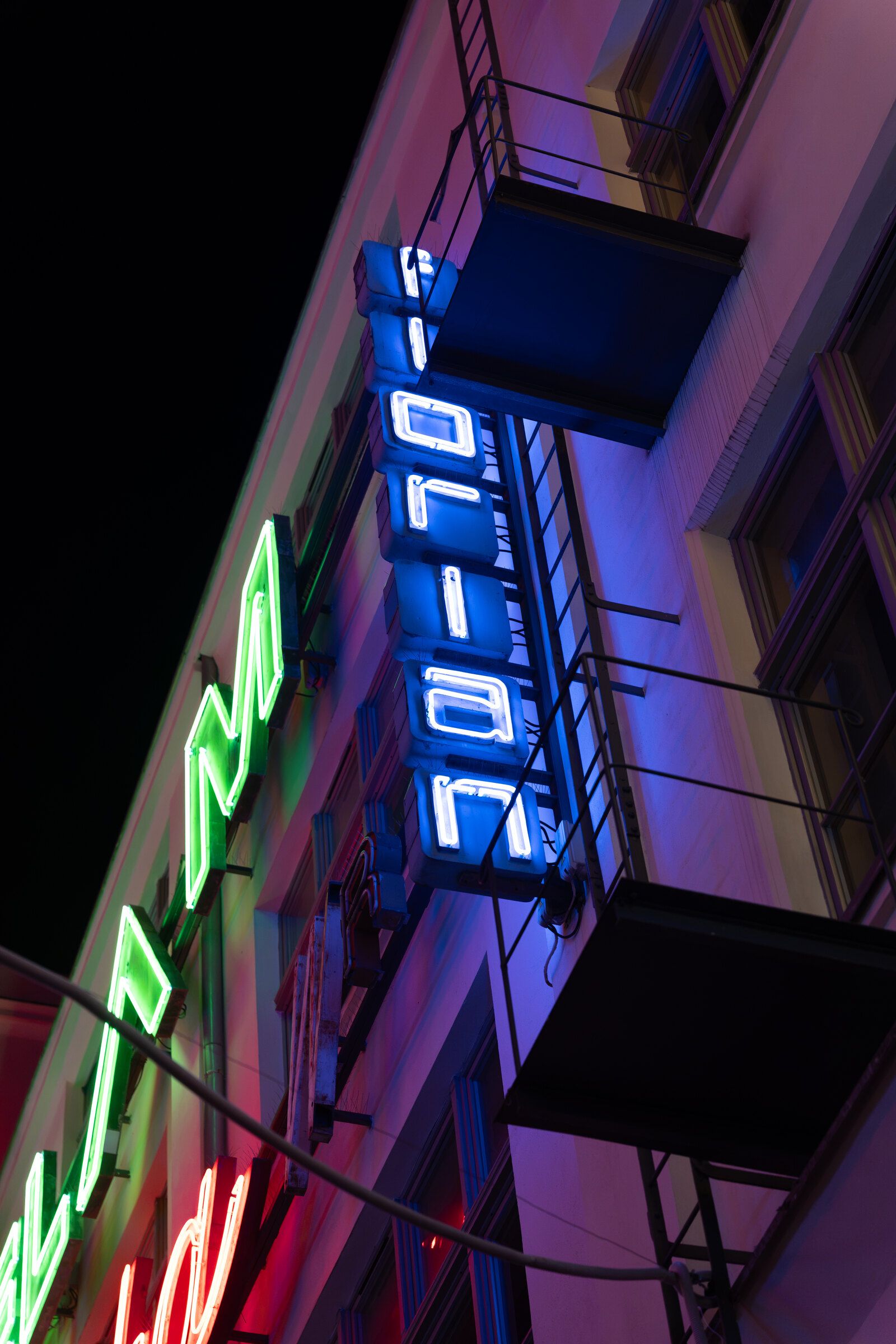 Svislý modrý neon na fasádě domu v noci